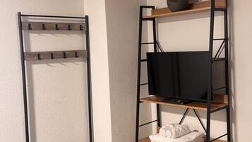 A room with a bunk bed, a TV on a shelf, and a vase with flowers.