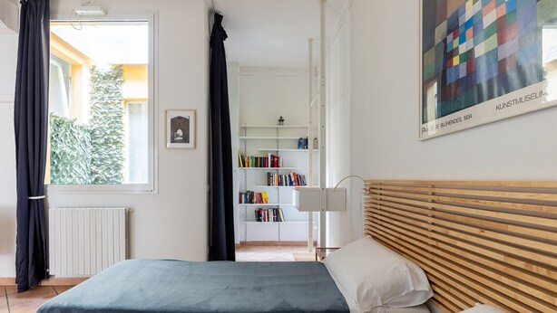 Un dormitorio con una cama, una estantería y un cuadro.