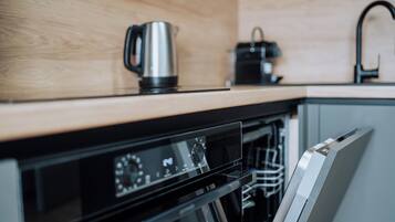 Une cuisine équipée d’une bouilloire en acier inoxydable, d’une machine à café et d’un lave-vaisselle.