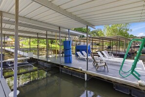 A covered outdoor pool area with lounge chairs, a blue barrel, and a green hose.