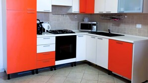 Eine Küche mit weißen und orangefarbenen Schränken, einer Mikrowelle, einem Herd und einem Spülbecken.