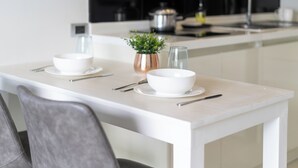 A modern kitchen with a white countertop, two white bowls, a small plant, and a glass. - Naiharan Apartment UTN D604 near Beach (Rawai)