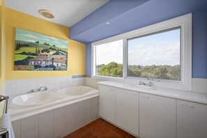 Relax in a spacious bathtub under a large window with a view of the surrounding landscape.