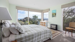 Quarto com cama, cadeira, aquecedor e uma janela grande com vista.