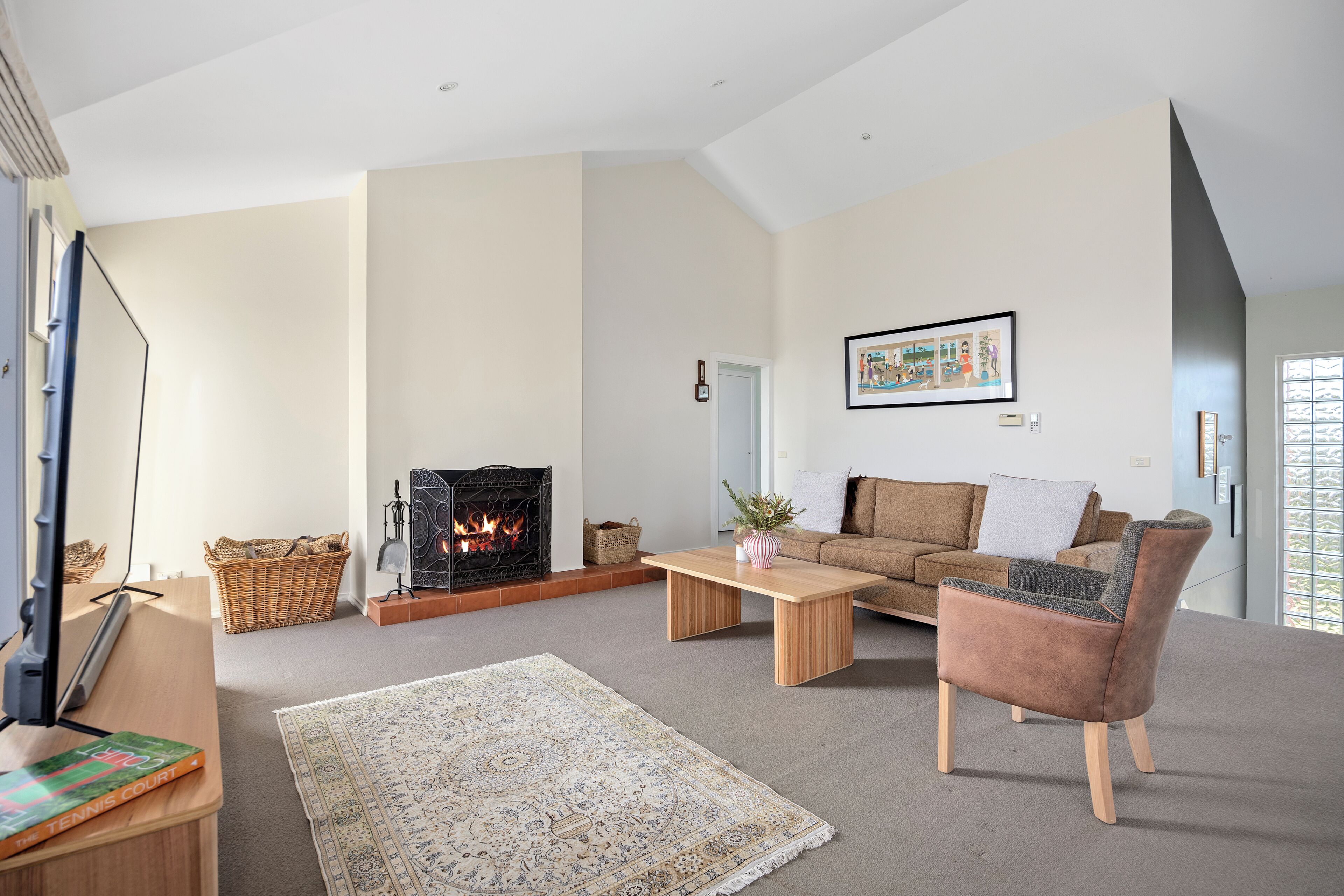A living room with a fireplace, a sofa, a coffee table, and a rug.