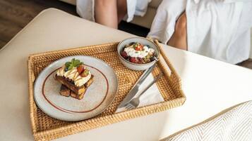 Una bandeja con un postre y un bol de parfait de yogur sobre un tapete tejido.