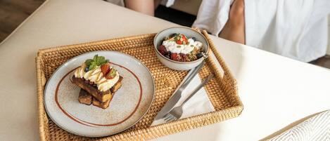 A tray with a dessert and a bowl of yogurt parfait on a woven mat.