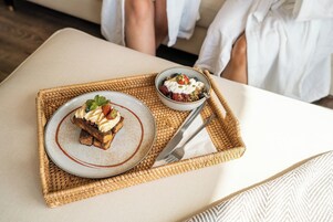 Una bandeja con un postre y un bol de parfait de yogur sobre un tapete tejido.