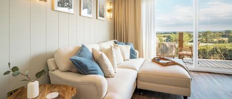 A modern living room with a sofa, a coffee table, and a view of the outdoors.