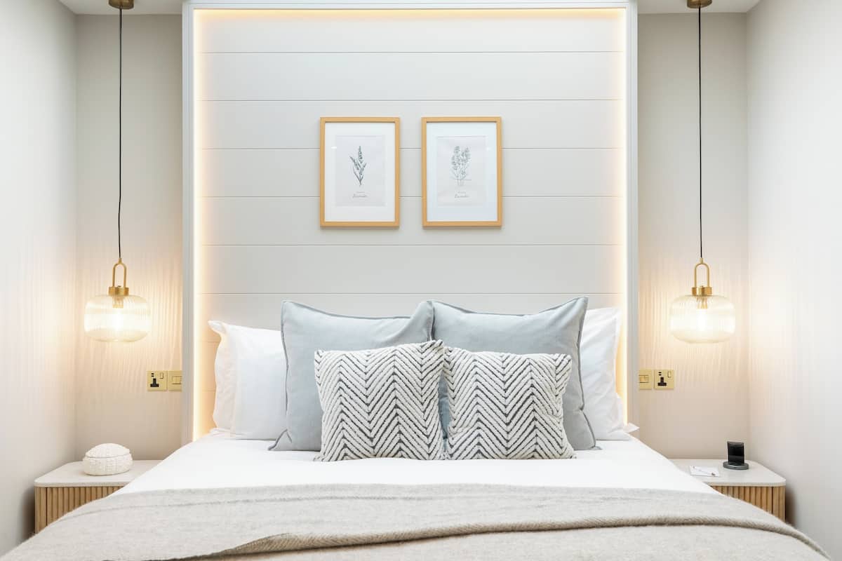 A modern bedroom with a bed, two bedside tables, and two wall-mounted light fixtures.