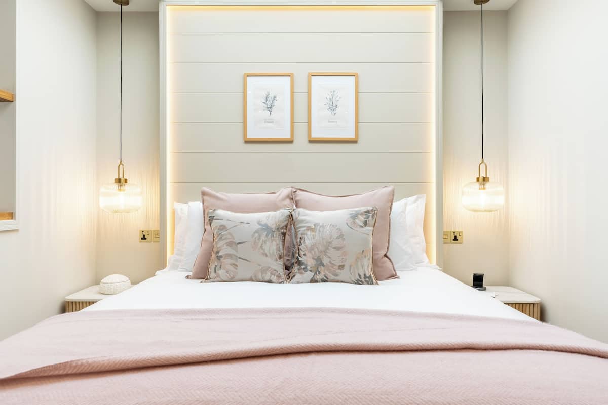 A neatly arranged bedroom with a large bed, two bedside tables, and wall-mounted light fixtures.