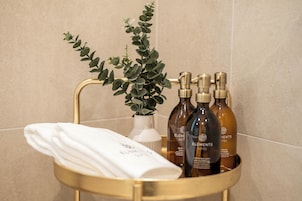 Un baño con tocador dorado, una toalla blanca y productos para el cuidado de la piel Elemis.