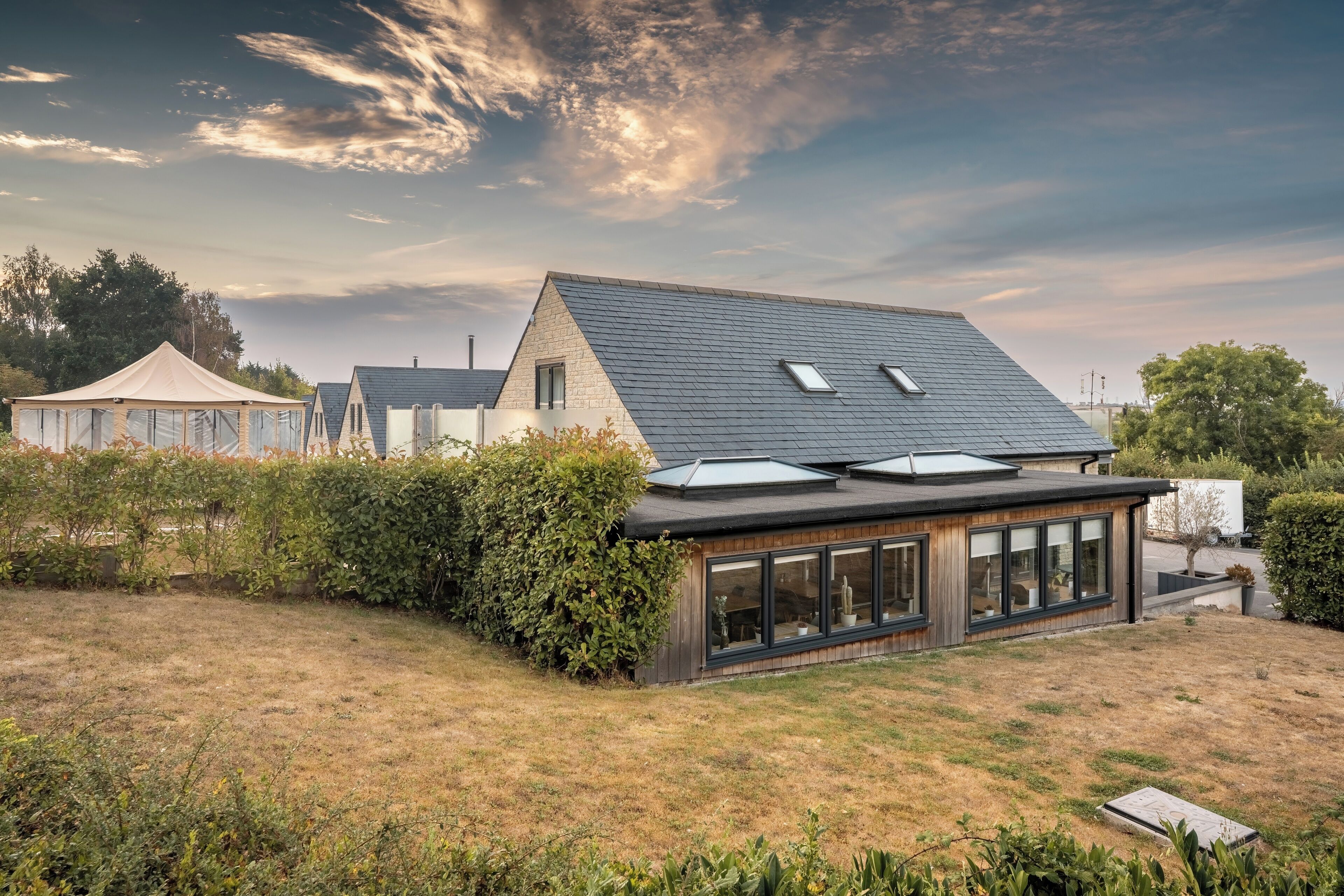 A modern house with a sloped roof, large windows, and a well-maintained lawn.