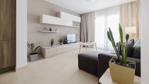 Una sala de estar moderna con sofá, mesa de centro, televisor y plantas en macetas.