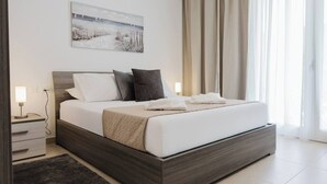Un dormitorio moderno con una cama grande, una mesita de noche con lámpara y un cuadro en la pared.