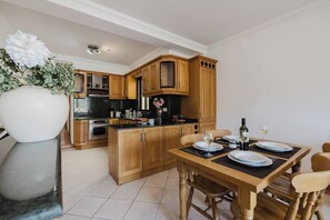A modern kitchen with wooden cabinets, a central island, and a dining area set for four.