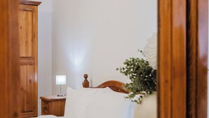 Un dormitorio con una cama de madera, una mesita de noche con lámpara y un armario de madera.