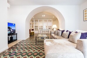 Una sala de estar con sofá, televisión y alfombra estampada.