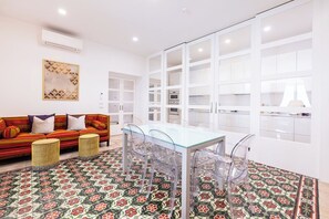 Una sala de estar moderna con un sofá, una mesa de comedor de vidrio y un piso estampado.