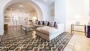 Un salon moderne avec un canapé, une table basse en verre et un sol à motifs.