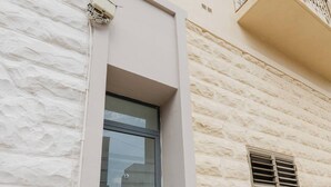 A building facade with a textured stone exterior, a door with a glass panel, and a small window with shutters.