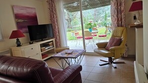 Un salon avec un téléviseur, un canapé en cuir et un fauteuil jaune.