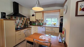 Une cuisine avec une table en bois, des chaises, une cuisinière, un évier et une fenêtre.