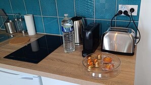 Een keukentrap met een broodrooster, een waterkoker, een waterfles en een glazen schaal met snacks.