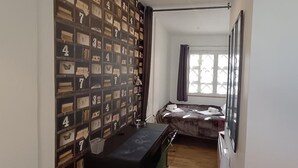 Ein Schlafzimmer mit Bett, Kleiderschrank, Schreibtisch und einem Fenster mit Vorhängen.