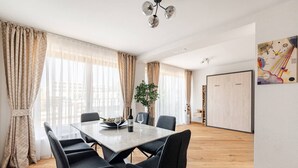 A modern dining area with a wooden floor, a dining table with six chairs, and a potted plant. - Marllon Suites – Verso Apartment (Lörrach)