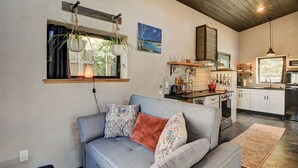 A cozy living room with a grey sofa, patterned cushions, a hanging plant, and a painting of a night sky. - Modern mountain bungalow with private patio + epic Mt. Princeton views (Buena Vista)