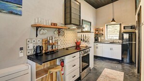 A modern kitchen with a black countertop, white cabinets, a stainless steel refrigerator, and a wooden ceiling. - Modern mountain bungalow with private patio + epic Mt. Princeton views (Buena Vista)
