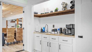 Una cocina moderna con armarios blancos, encimera de madera y varios electrodomésticos.