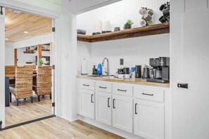 Una cocina moderna con armarios blancos, encimera de madera y varios electrodomésticos.