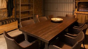 A rustic dining area with a wooden table, wicker chairs, and a hanging light fixture. - Villavia Residence - Sorocco Villa (West Mani)
