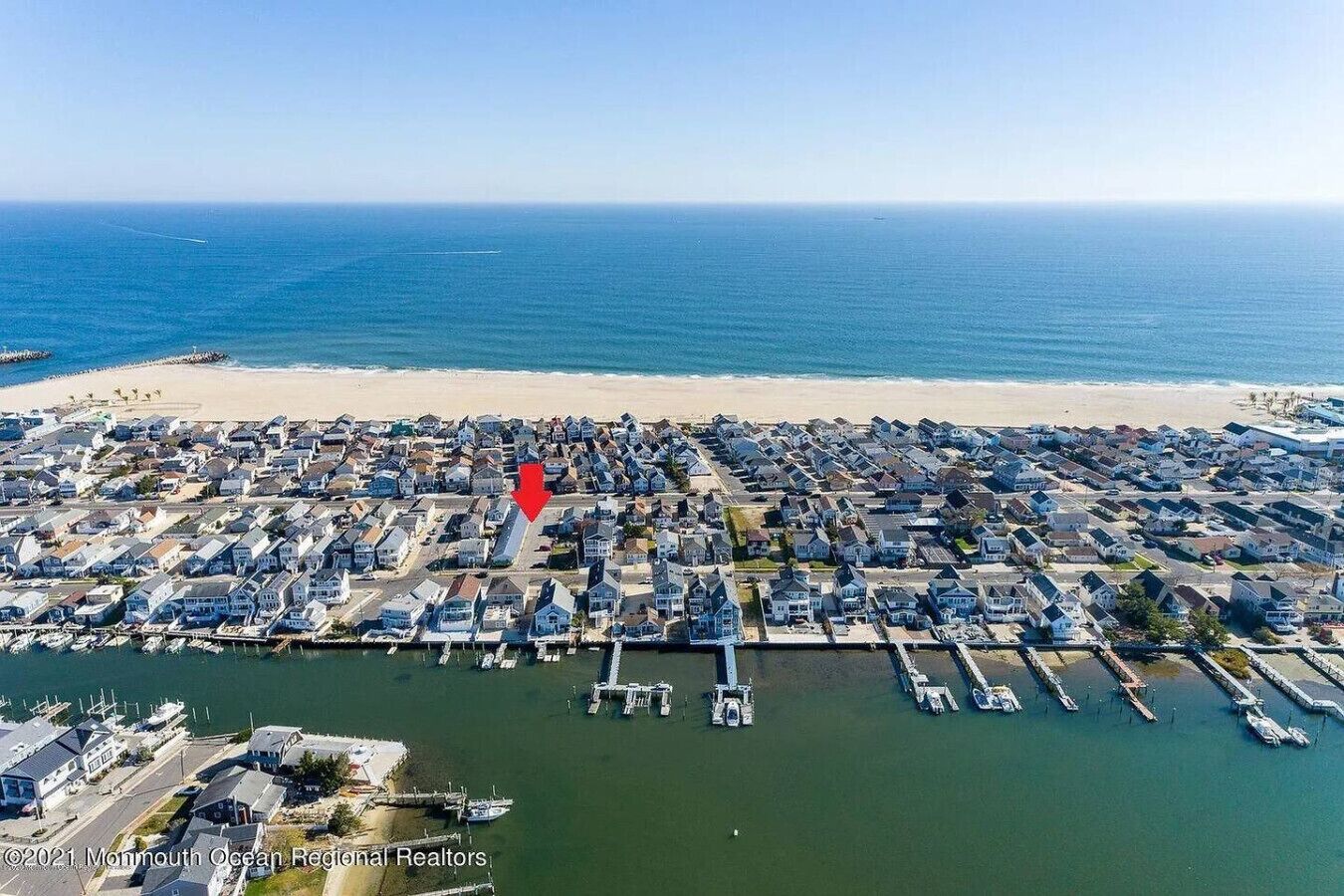 Vista aérea de una zona residencial costera con casas, un puerto deportivo y una playa.