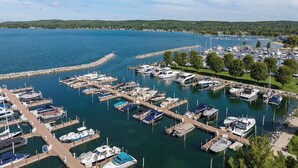 Un port de plaisance où sont amarrés de nombreux bateaux, entouré d’une zone riveraine agrémentée d’arbres et bordé par une côte lointaine.