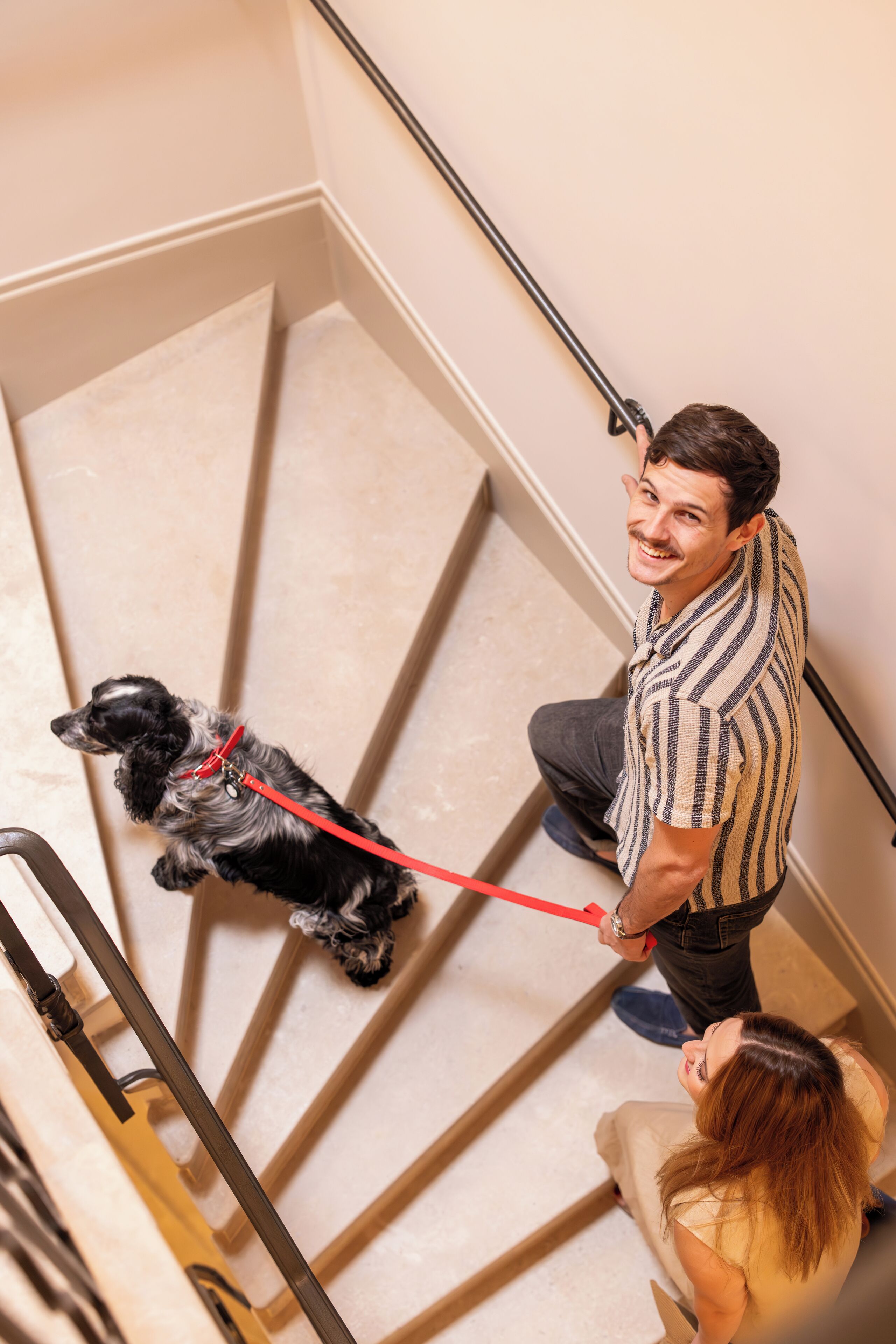 A person descending a staircase with a dog on a leash.