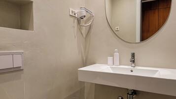 Un baño moderno con lavamanos, espejo y retrete blancos.