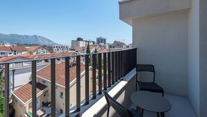 A balcony with a table and chairs, overlooking a cityscape with buildings and mountains. - Lucciola Boutique Rooms (Budva)