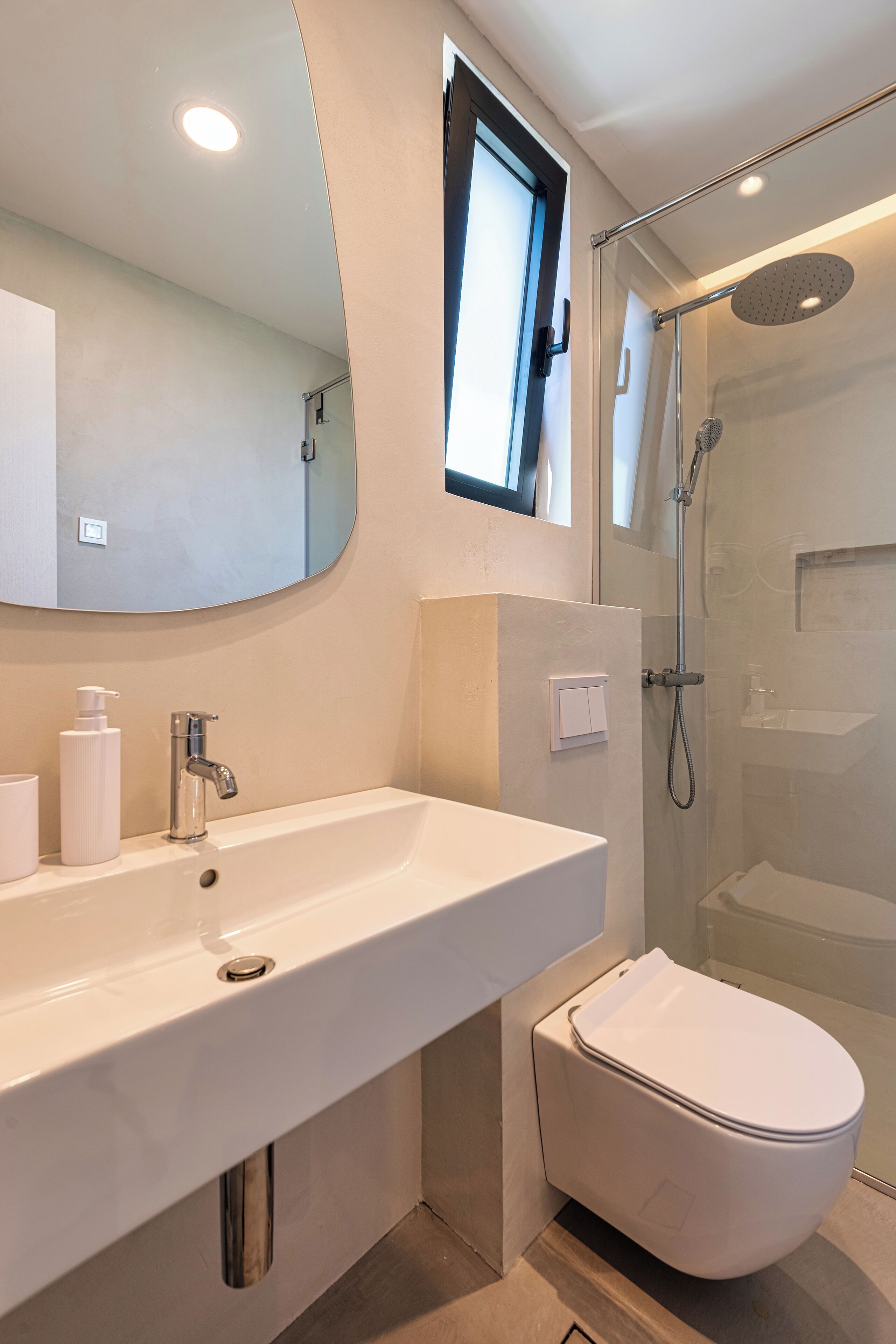 A modern bathroom with a large sink, a toilet, a shower, and a mirror.