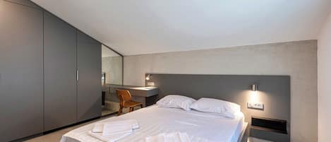 Una habitación de hotel moderna con una cama grande, un escritorio y una silla.