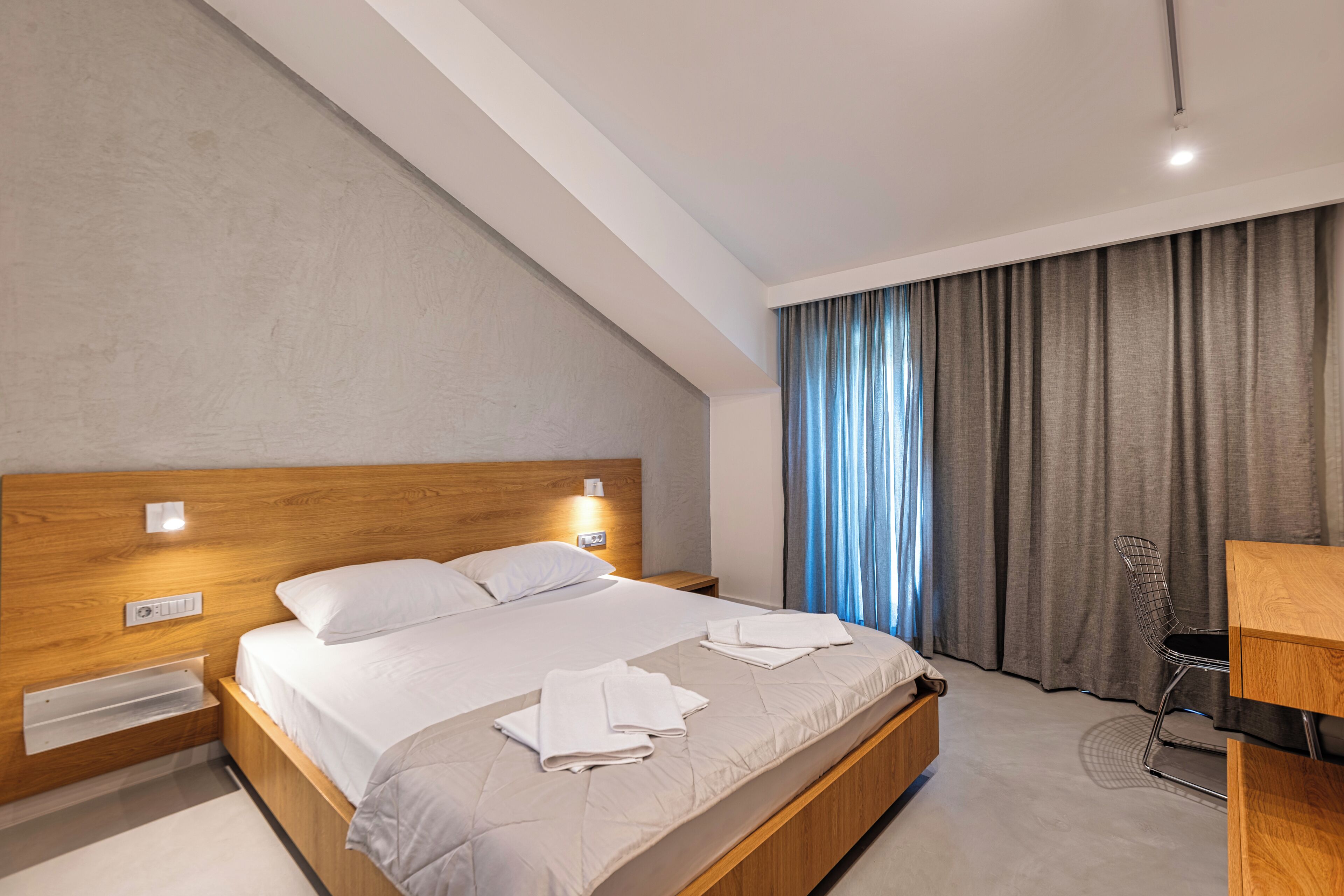 Une chambre d’hôtel moderne avec un lit en bois, un bureau et une chaise.