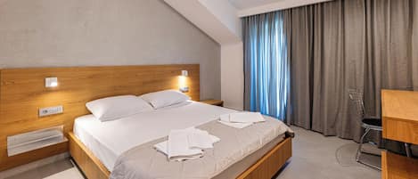 A modern hotel room with a wooden bed, a desk, and a chair.
