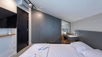 A modern hotel room with a bed, a desk, and a wardrobe.