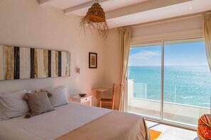 A bedroom with a large bed, a small desk, a chair, and a view of the sea through a large window. - KITE HOUSE DAKHLA  (Dakhla)