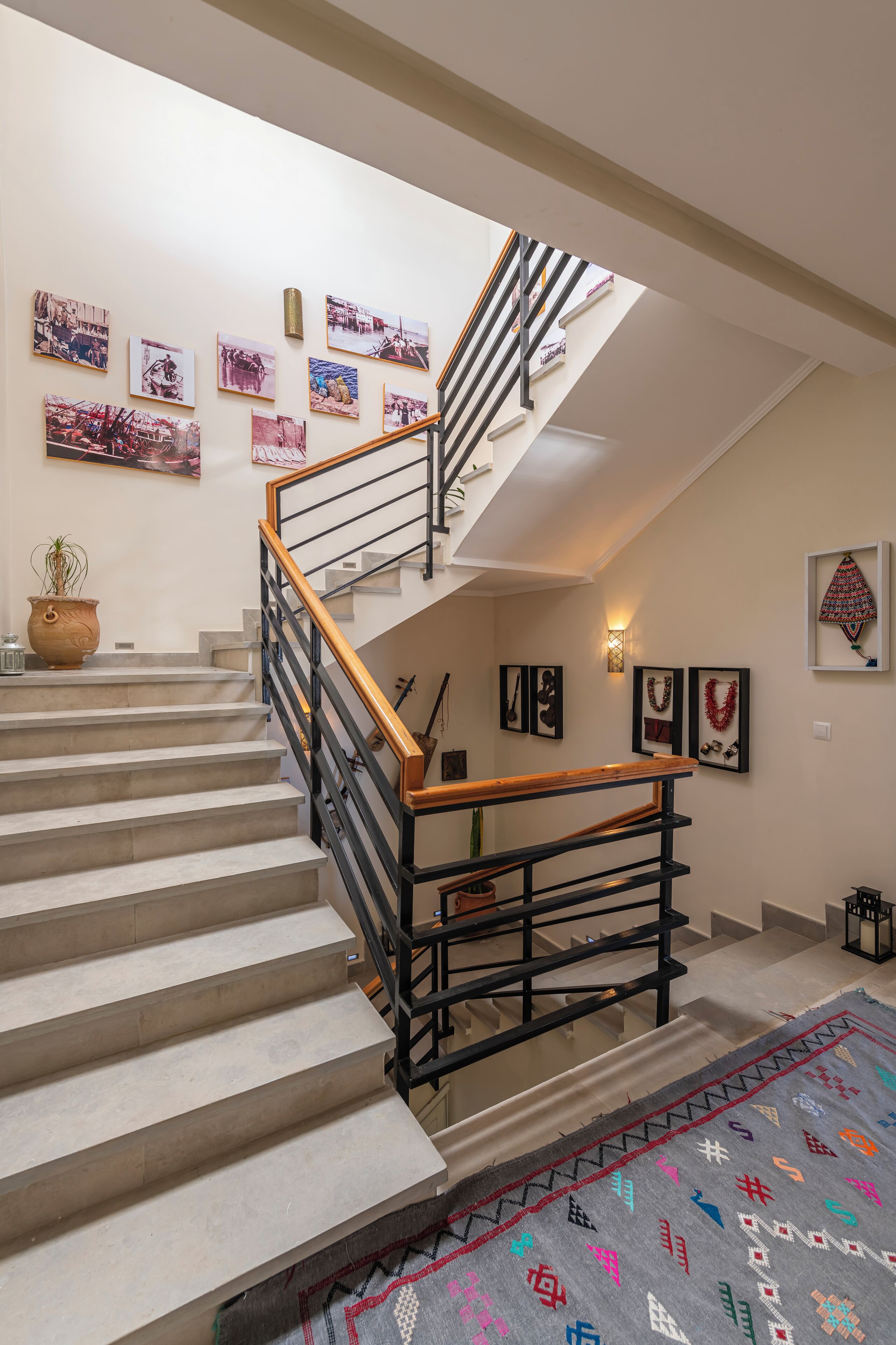 Una escalera con barandilla de madera y balaustradas de metal negro, que conduce a un piso superior.