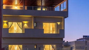 Un edificio de varios pisos con ventanas y balcones iluminados, que presenta un diseño arquitectónico moderno.
