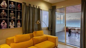 Un sofá amarillo en una sala de estar con un ventanal grande con vista al mar.