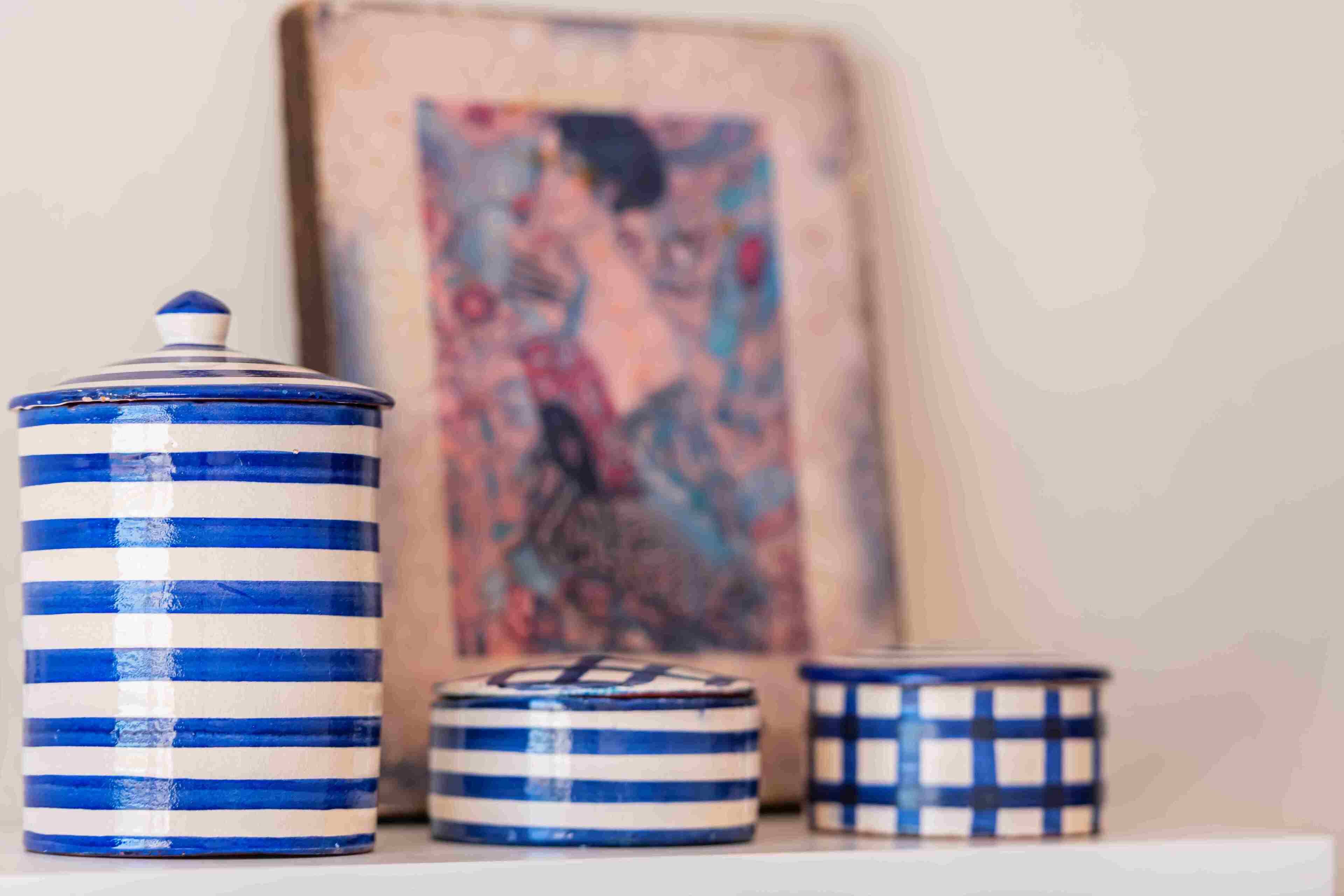 Three ceramic containers with blue and white stripes on a shelf.